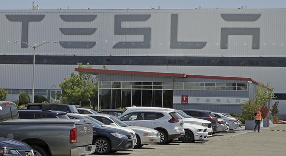 A masked man walks in the Tesla plant parking lot Monday, May 11, 2020, in Fremont, Calif. The parking lot was nearly full at Tesla&#039;s California electric car factory Monday, an indication that th ...
