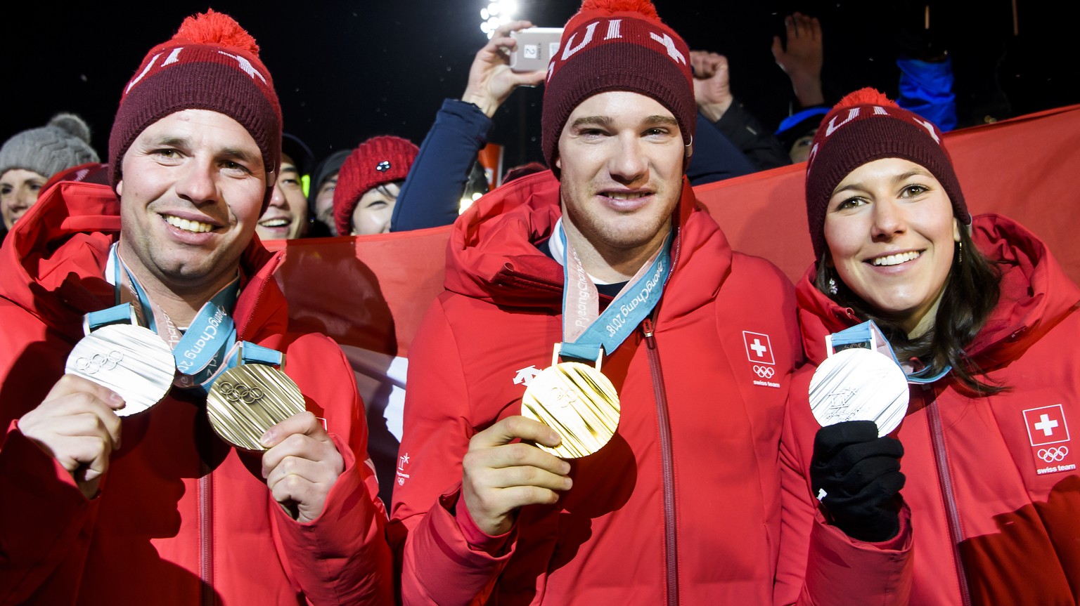 Silver and Bronze medals, Beat Feuz of Switzerland, left, Gold medal, Dario Cologna of Switzerland, center, and Silver medal, Wendy Holdener of Switzerland, right, celebrate at the House of Switzerlan ...