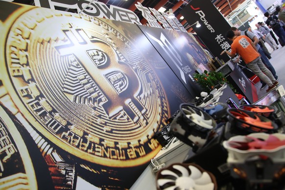 epa06785821 A bitcoin logo is seen next to computer fans during the Computex 2018 in Taipei, Taiwan, 05 June 2018. The Computex 2018 event will run from 05 June to 09 June 2018 and will exhibit innova ...