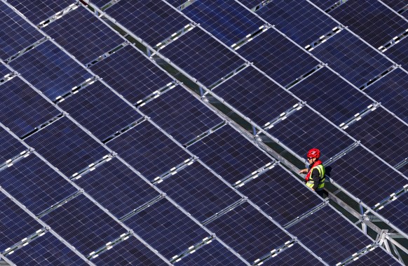 epa07906927 A worker assembles floating barges with solar panels on the Lac des Toules, an alpine reservoir lake, in Bourg-Saint-Pierre, Switzerland, 08 October 2019 (issued 09 October 2019) Upon comp ...