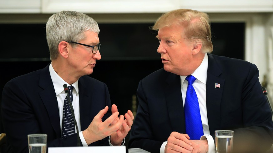 FILE - In this Wednesday, March 6, 2019 file photo, President Donald Trump talks to Apple Inc. CEO Tim Cook during the American Workforce Policy Advisory Board&#039;s first meeting in the State Dining ...