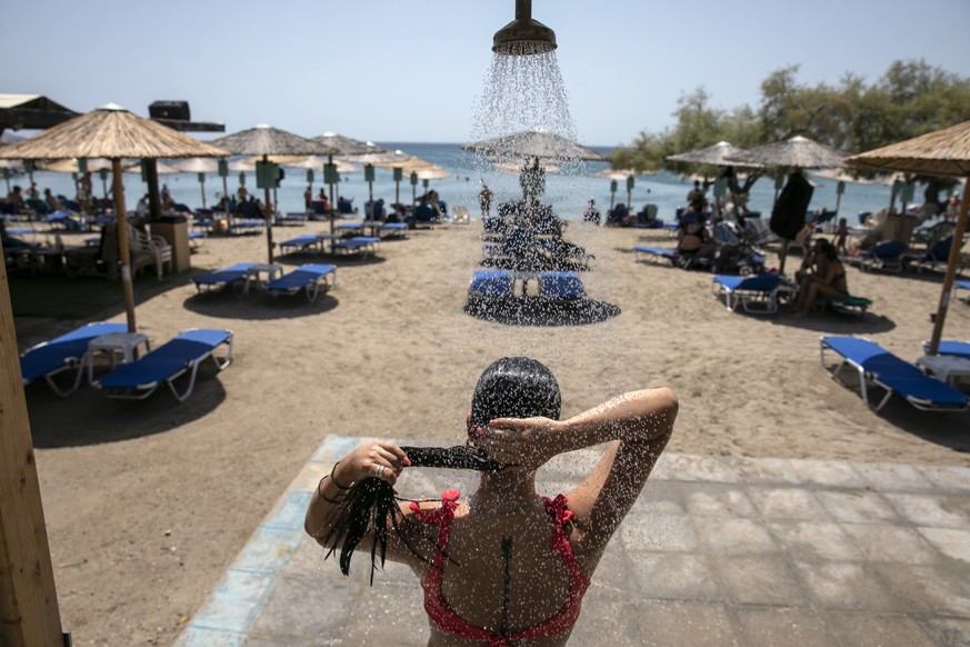 A woman takes a shower at a beach of Lagonissi village, a few miles southwest of Athens, on Thursday, July 29, 2021. One of the most severe heat waves recorded since 1980s scorched southeast Europe on ...