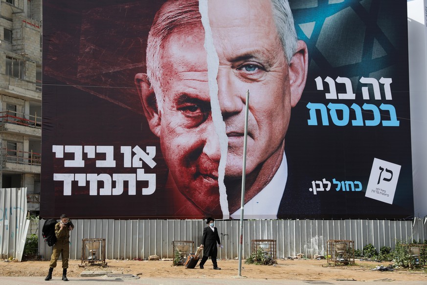 epa09073380 People pass by a large election billboard showing Israeli Prime Minister Benjamin Netanyahu and leader of the Blue and white party Beny Gantz in Bnei Brak, near Tel Aviv, Israel, 14 March  ...