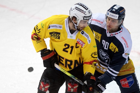Ambri&#039;s player Jannik Fischer, right, fights for the puck with Bern&#039;s player Simon Moser, during the preliminary round game of National League A (NLA) Swiss Championship 2020/21 between HC A ...