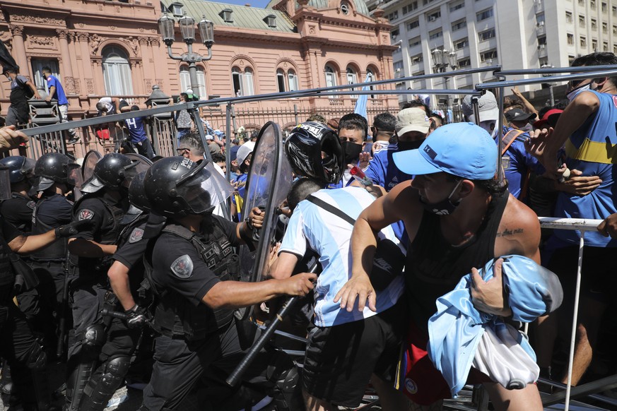 Soccer fans scuffle with police guarding the presidential palace, where Diego Maradona is lying in state, in Buenos Aires, Argentina, Thursday, Nov. 26, 2020. The Argentine soccer great who was among  ...