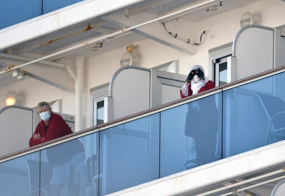 epa08210262 Passengers of the Diamond Princess cruise ship stand on cabin balconies near the Daikoku Pier Cruise Terminal in Yokohama, Japan, 11 February 2020. According to latest media reports, 135 p ...