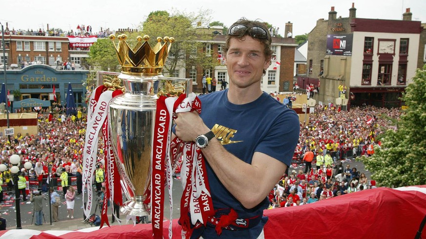 Arsenal goalkeeper Jens Lehmann holds up the English Premiership trophy to thousands of jubilant fans outside Islington Town Hall in North London, Sunday May 16, 2004, during their victory parade. (AP ...
