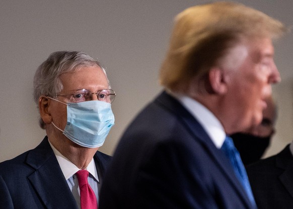 epa08432691 Senate Majority Leader Mitch McConnell, R-KY, listens as US President Donald J. Trump speaks to reporters after attending the weekly Senate Republican luncheon on Capitol Hill in Washingto ...