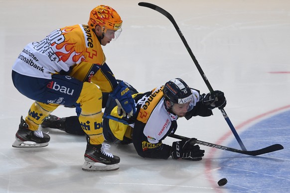 Davos&#039;s player Perttu Lindgren, left, fights for the puck with Ambri&#039;s player Marco Mueller, right, during the preliminary round game of National League Swiss Championship between HC Ambri P ...