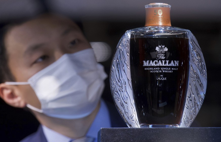Specialist Christopher Pong displays a Macallan Lalique 50 year-old whisky, expecting to sell for US$$122,500, during a Bonhams auction preview in Hong Kong Thursday, Jan. 28, 2021. Despite the econom ...