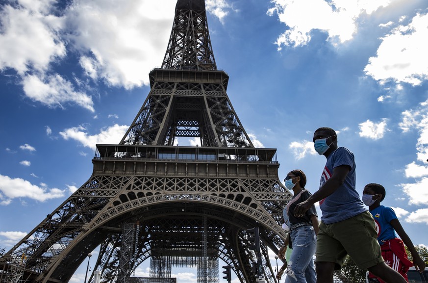 epaselect epa08629174 A family wearing protective face masks walk near the Eiffel Tower, in Paris, France, 27 August 2020. French Prime Minister Jean Castex has announced that measures are being taken ...