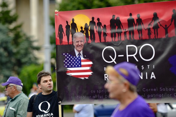 Romanian supporters of QAnon take part in a rally against the government&#039;s measures to prevent the spread of COVID-19 infections, like wearing a face mask, in Bucharest, Romania, Monday, Aug. 10, ...