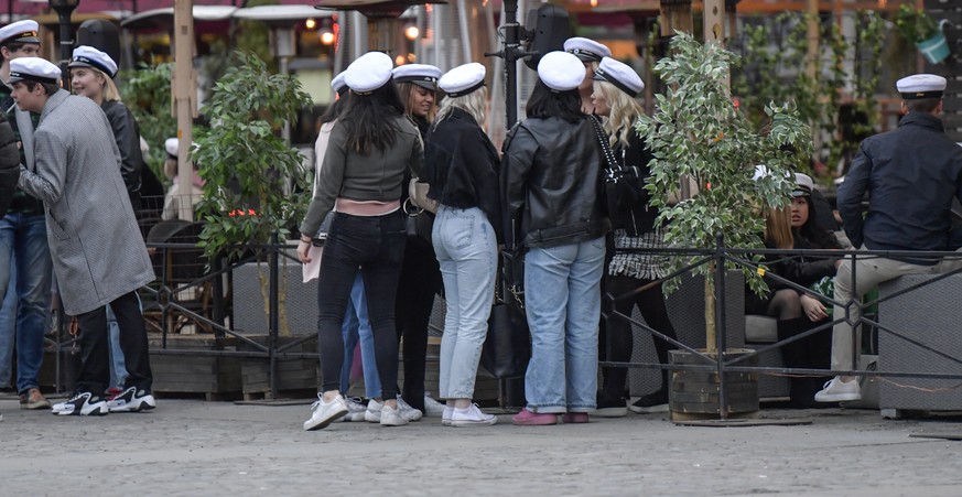 epa08383798 Senior high school students celebrate their graduation wearing the traditional white caps while drinking on the terrace of a restaurant in downtown Stockholm, Sweden, 24 April 2020 (issued ...