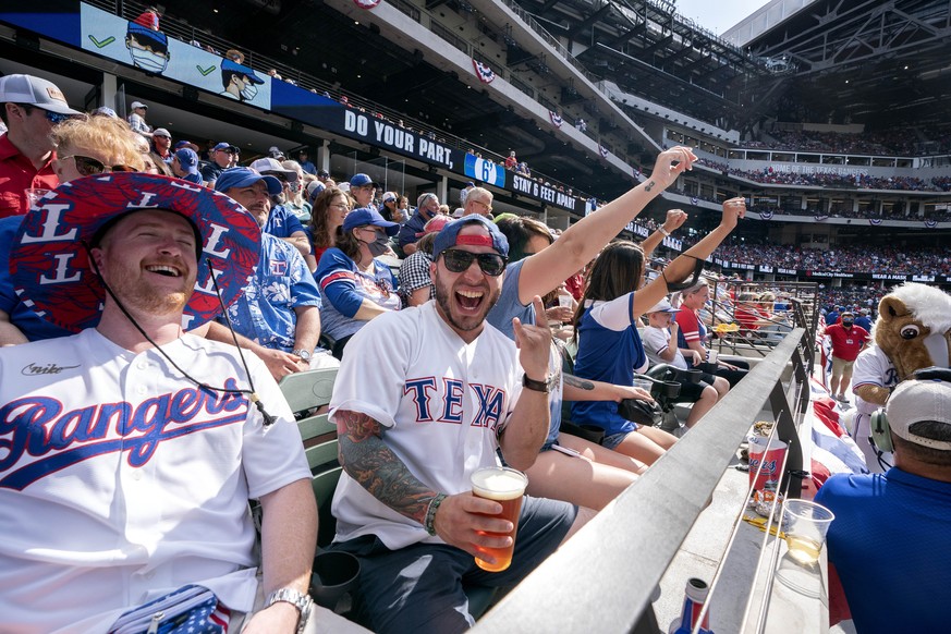 Texas Rangers fans Cameron Leverett, left, and Anthony Sosa celebrate during the fourth inning of a baseball game against the Toronto Blue Jays Monday, April 5, 2021, in Arlington, Texas. (AP Photo/Je ...