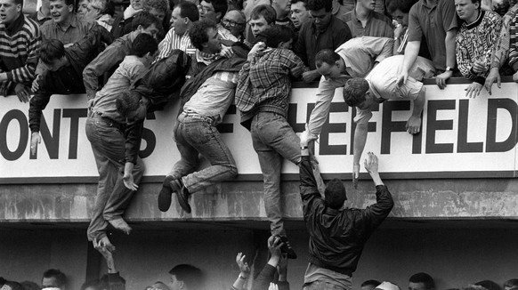 Liverpool fans climb the terraces in a desperate bid to escape severe crushing at the Leeping Lane end at Hillsborough on April 15, 1989, during the FA Cup semi-final between Liverpool and Nottingham  ...