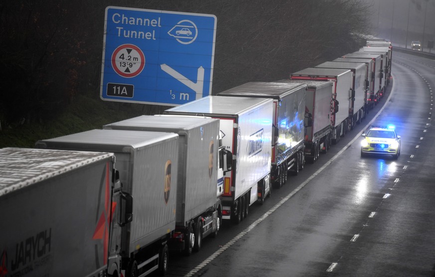 epa08897802 A police car patrols lorries headed to the Port of Dover which are stacked along the M20 motorway in Kent, Britain, 21 December 2020. France has closed its border with the UK for 48 hours  ...