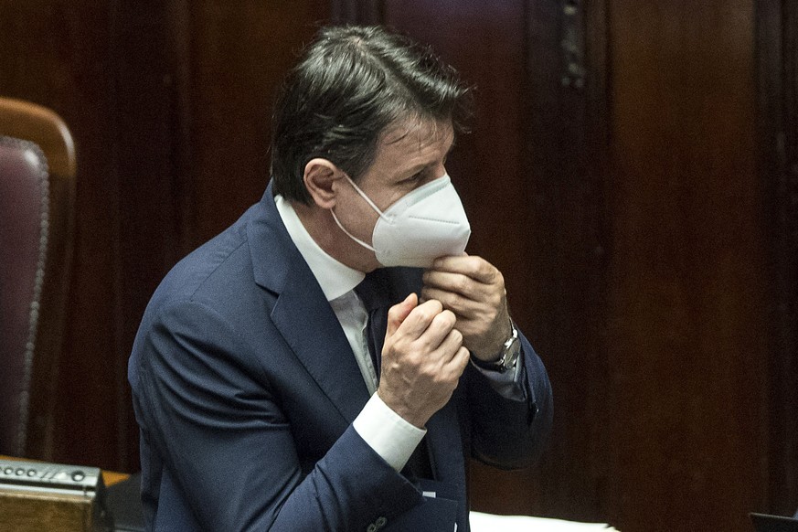 Italian Premier Giuseppe Conte adjusts his face mask as he arrives at the Lower Chamber of Deputies of the Italian Parliament, in Rome, Tuesday, April 21, 2020. Conte said the easing of lockdown restr ...