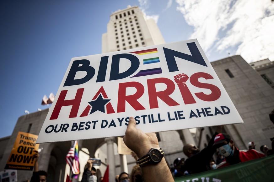 epa08806229 A man holds a placard reading &#039;Biden Harris Our Best Days Still Lie Ahead&#039; as people celebrate after news organizations called the US 2020 presidential election for Joe Biden, de ...