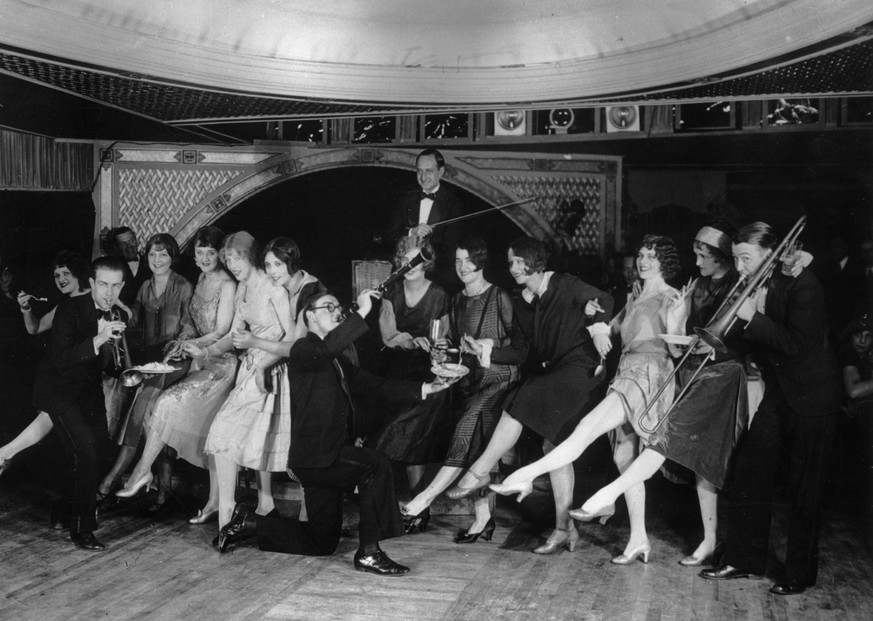 22nd January 1926: Female flappers kicking, dancing, and having fun while musicians perform during a Charleston dance contest at the Parody Club. (Photo by Hulton Archive/Getty Images)