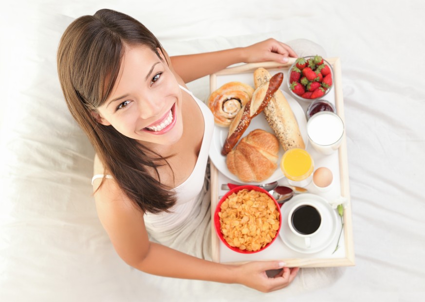 Ein eher mittelmässig gelungenes Stock-Foto, das eine Frau beim Frühstück in ihrem Bett zeigen soll. Wenn sie nur nichts auf das weisse Laken schüttet ...
