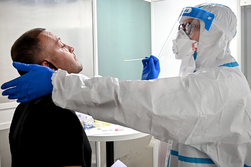 epa08568621 A traveler gets his swab sample collected in a walk-in test center for coronavirus at the International Airport in Duesseldorf, Germany, 27 July 2020. Within a few days, a test centre has  ...