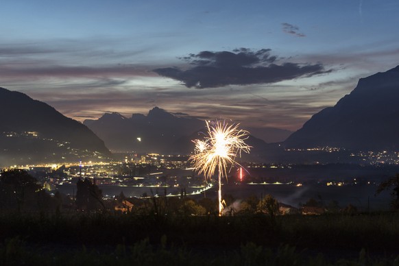 Umgeben von Hoehenfeuer rund um das Churer Rheintal expodiert ein Feuerwerk zum Ausklang des Nationalfeiertages am Freitag, 1. August 2014, in Igis. (KEYSTONE/Arno Balzarini)