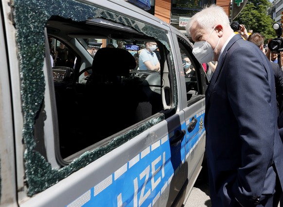 epa08501808 German Interior Minister Horst Seehofer looks at a damaged police car during a visit to the downtown shopping area in Stuttgart, 22 June 2020. Several hundreds of rioting youths vandalized ...