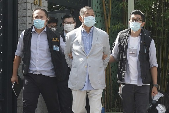 Hong Kong media tycoon Jimmy Lai, center, who founded local newspaper Apple Daily, is arrested by police officers at his home in Hong Kong, Monday, Aug. 10, 2020. Hong Kong police arrested Lai and rai ...