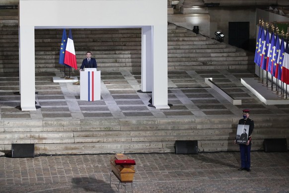 epa08762740 French President Emmanuel Macron delivers his speech in front of the coffin of slain teacher Samuel Paty is carried in the courtyard of the Sorbonne university during a national memorial e ...