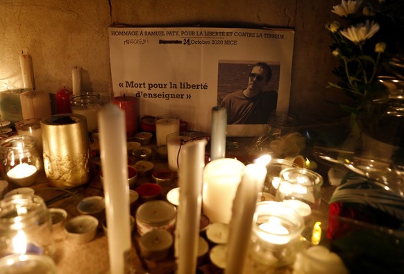 epa08763019 Candles, messages and floral tributes are placed to pay respect to the late teacher Samuel Paty on the Promenade des Anglais in Nice, France, 21 October 2020. French history teacher Samuel ...
