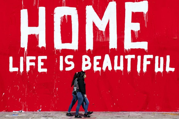 epa08348852 Two women wearing face masks walk past a mural reading &#039;Stay Home Life Is Beautiful&#039; amid the coronavirus pandemic in Los Angeles, California, USA, 07 April 2020. Countries aroun ...