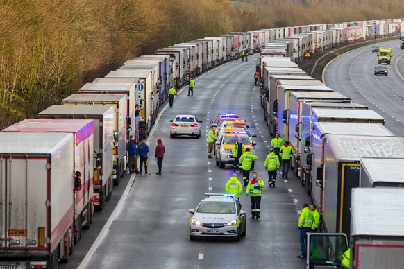 epa08901076 Police and emergency services distribute water and supplies to queues of stationary lorries on the M20 motorway between Ashford and Folkestone in Kent, Britain, 23 December 2020. France cl ...