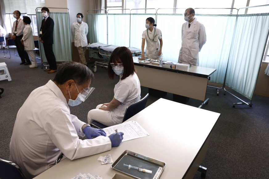 A medical worker checks the form of his colleague before giving her a dose of the COVID-19 vaccine at Tokyo Medical Center in Tokyo Wednesday, Feb. 17, 2021. Japan&#039;s first coronavirus shots were  ...