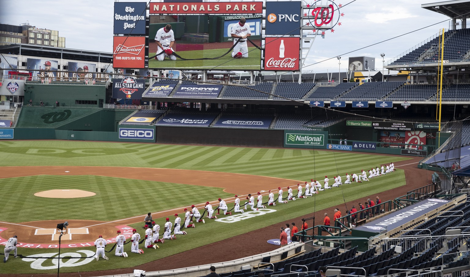 Members of Washington Nationals and against the New York Yankees kneel and hold a piece of black fabric before an opening day baseball game at Nationals Park, Thursday, July 23, 2020, in Washington. ( ...