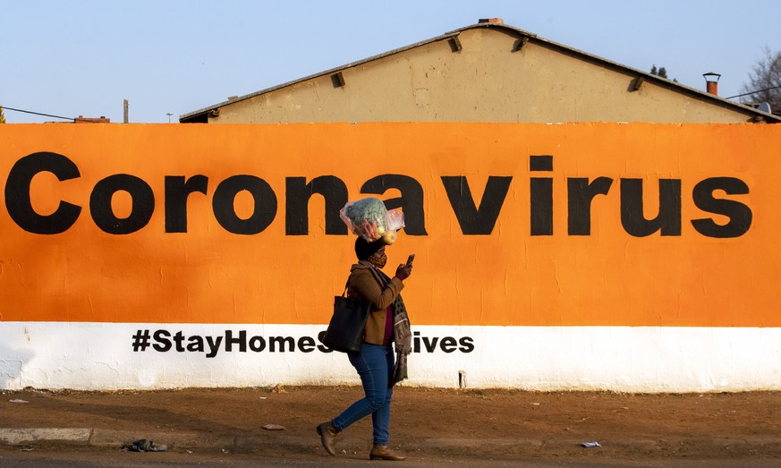 FILE - In this Friday June 19, 2020, a woman wearing a face mask passes a coronavirus billboard carrying a message in a bid to prevent the spread of the virus. South Africa&#039;s Health Minister Zwel ...