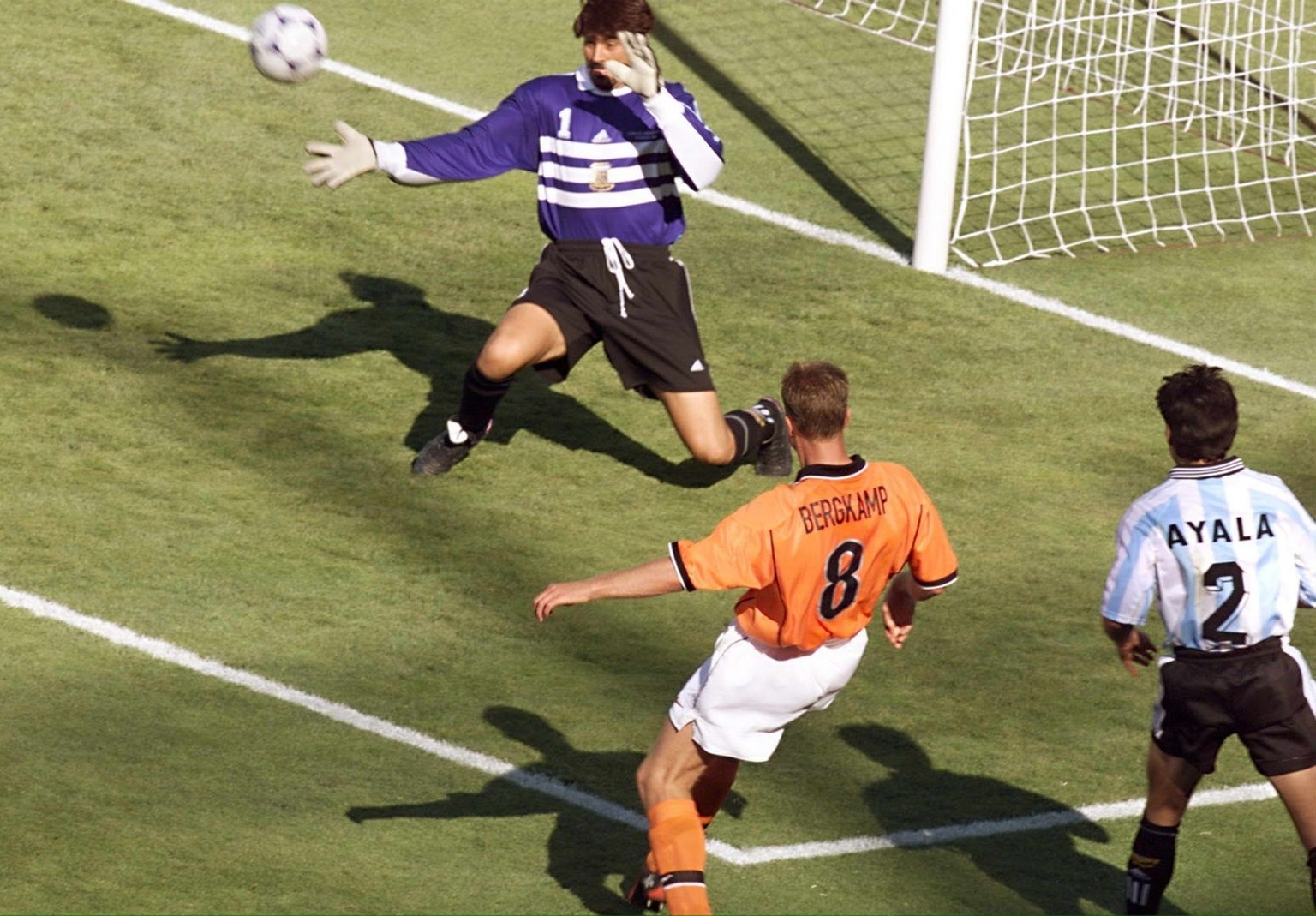 Dutch forward Dennis Bergkamp kicks the ball past Argentinian goalkeeper Carlos Roa to score the victory goal as Argentinian defender Roberto Ayala looks on during their World Cup quarter-final match  ...