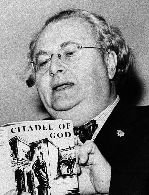 ** FILE ** Astrologer Louis De Wohl looks at a copy of his book &quot;The Citadel of God&quot; in this March 21, 1960 file pictrue taken in London. Desperate for a glimpse into Adolf Hitler&#039;s unp ...