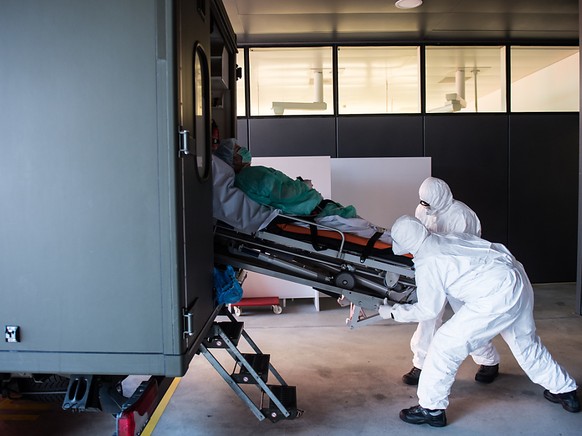 Das Tessin ist landesweit am stärksten vom Coronavirus betroffen: Soldaten der Schweizer Armee beim Transport eines Patienten mit Covid-19 am Eingang der Notaufnahme im Kantonsspital &#039;&#039;La Ca ...