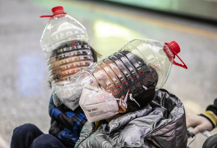 epaselect epa08185830 Childrean wear an improvised face protection made from water bottles in order to protect against the coronavirus at the airport arrival terminal in Guangzhou, Guangdong Province, ...