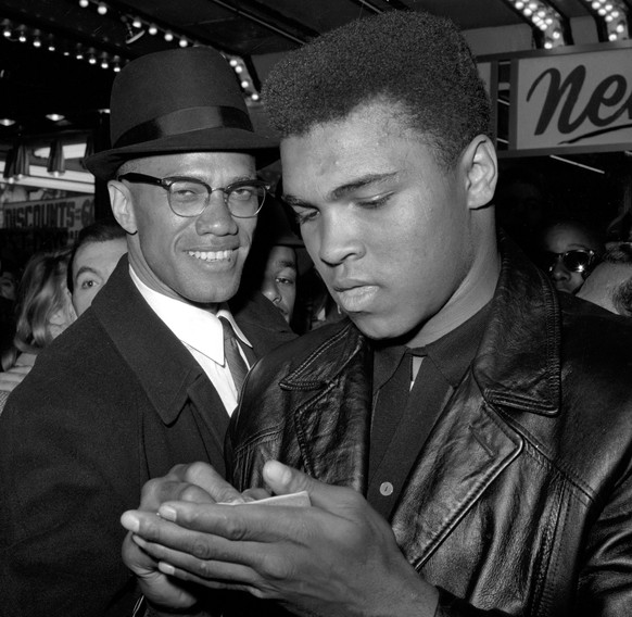 FILE - In this March 1, 1964 file photo, Muhammad Ali, world heavyweight boxing champion, right, stands with Malcolm X outside the Trans-Lux Newsreel Theater on Broadway at 49th Street in New York aft ...