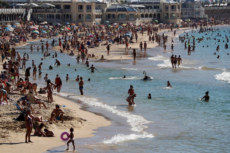 epa08586011 People enjoy a warm day at La Concha beach in San Sebastian, Basque Country, northern Spain, 05 August 2020. Many beaches in Spain are monitoring their capacity to avoid big crowds and new ...