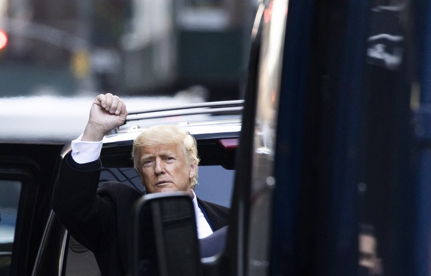 epa09064400 Former US President Donald J. Trump peers from behind vehicles in his motorcade to wave to people watching him depart Trump Tower in New York, New York, USA, 09 March 2021. Former Presiden ...