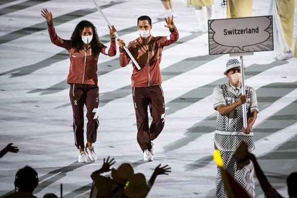 Switzerland&#039;s flag-bearers sprinter Mujinga Kambundji and epee fencer Max Heinzer celebrate during the opening ceremony of the 2020 Tokyo Summer Olympics at the National Stadium in Tokyo, Japan,  ...