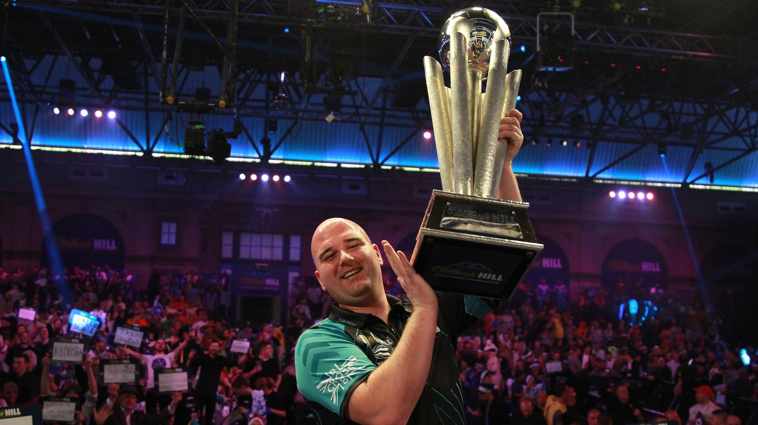 epa06413097 Rob Cross of England hoists the trophy after winning the PDC World darts final match over Phil Taylor of England at the Alexander Palace in North London, Britain, 01 January 2018. Phil Tay ...