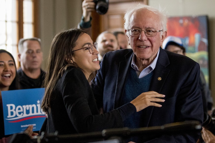 Democratic presidential candidate former Sen. Bernie Sanders, I-Vt., smiles as he is welcomed to the podium by Rep. Alexandria Ocasio-Cortez, D-N.Y., left, at a campaign stop at La Poste, Sunday, Jan. ...