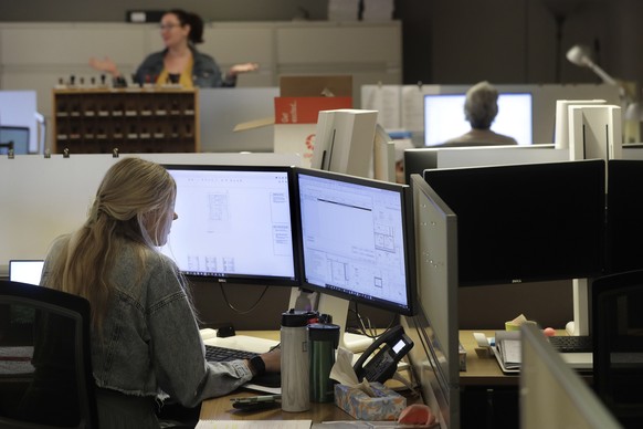 Architectural designer Erica Shannon, front, works at a computer as accounting manager Andrea Clark, top, speaks with a colleague at the design firm Bergmeyer, Wednesday, July 29, 2020, at the company ...