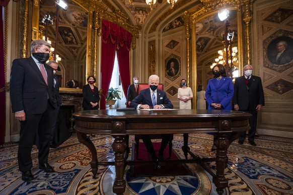 epaselect epa08953561 US President Joe Biden signs three documents including an Inauguration declaration, cabinet nominations and sub-cabinet noinations, as US Vice President Kamala Harris (R) watches ...