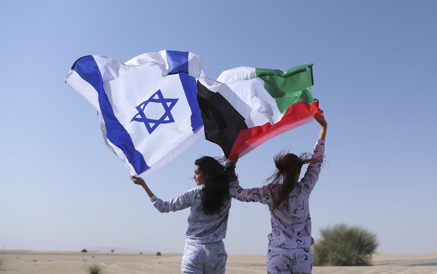 Israeli model May Tager, left, holds Israel&#039;s blue-and-white flag bearing the Star of David while next to her Anastasia Bandarenka, a Dubai-based model originally from Russia, waves the Emirati f ...