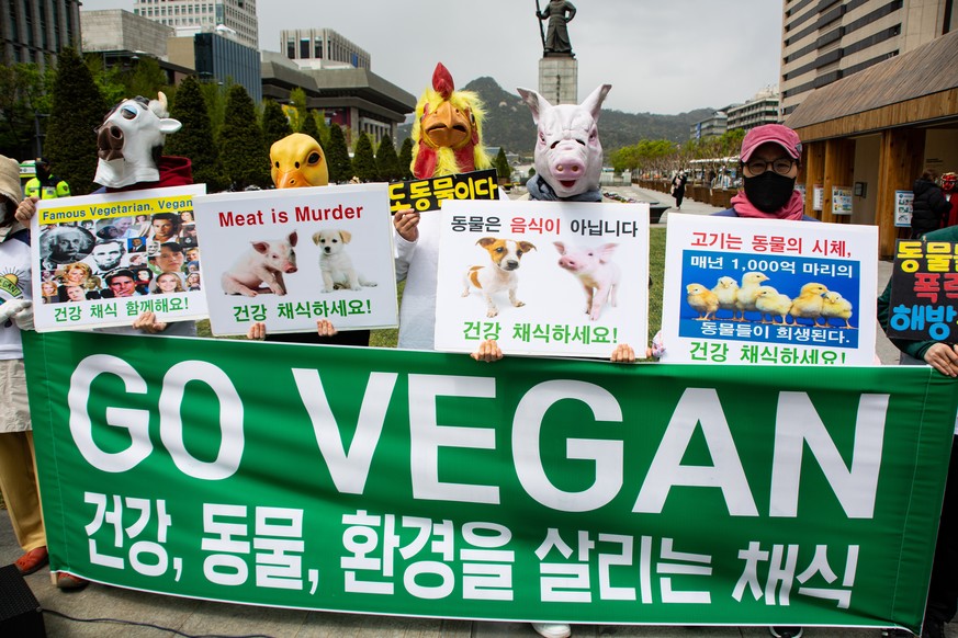 epa08376495 Members of the Vegan in Korea group, dressed as farm animals, hold placards and shout slogans during the 50th anniversary of Earth Day, at Gwanghwamun Square in Seoul, South Korea, 22 Apri ...