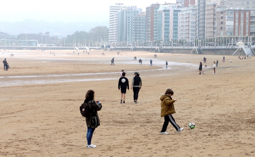 epa08385417 People walk on San Lorenzo beach with their children amid the ongoing coronavirus COVID-19 pandemic in Gijon, Spain, 26 April 2020, on the first day that minors have been allowed for an ho ...